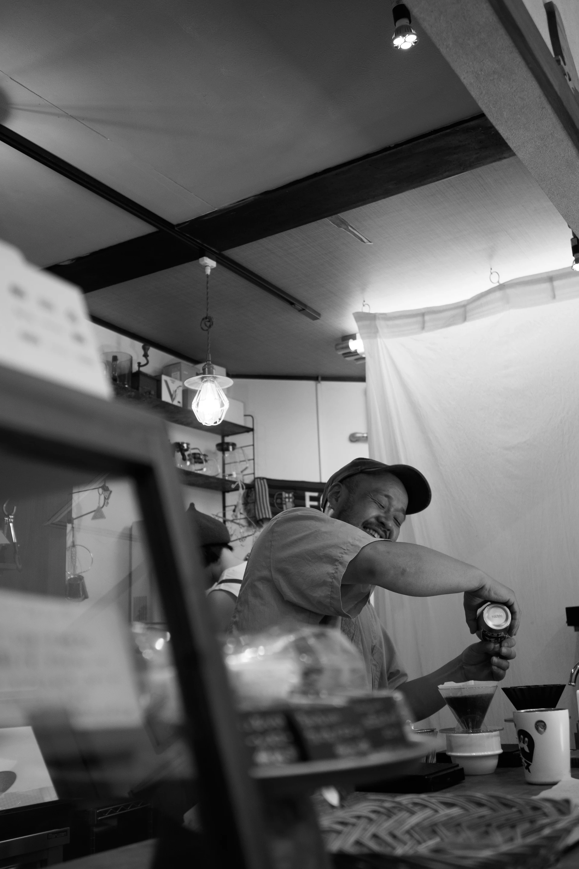 Un camarero prepara café con un filtro de goteo, sonriendo con los ojos cerrados.