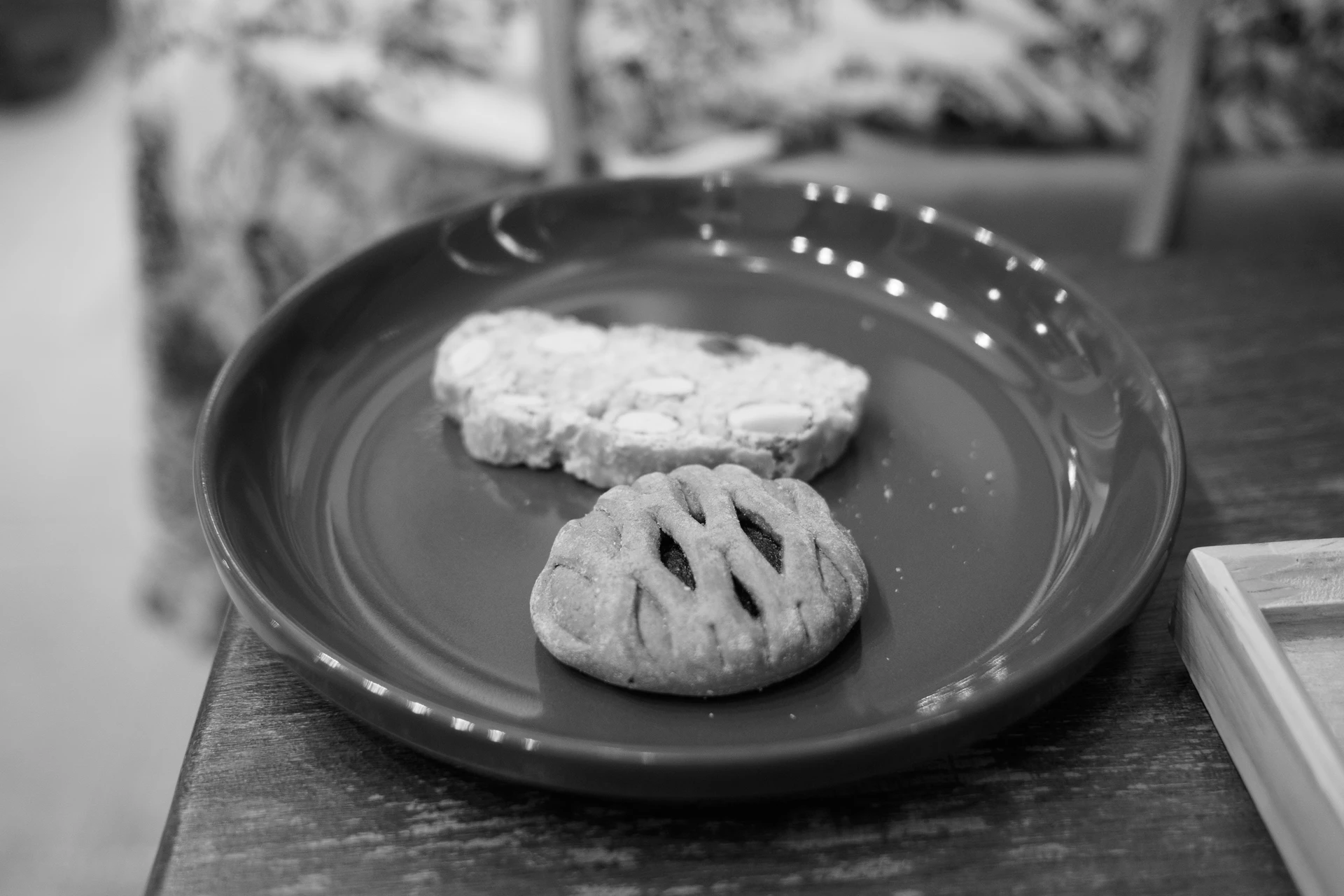 Un plato oscuro con dos galletas, una de almendra y otra con forma de red.